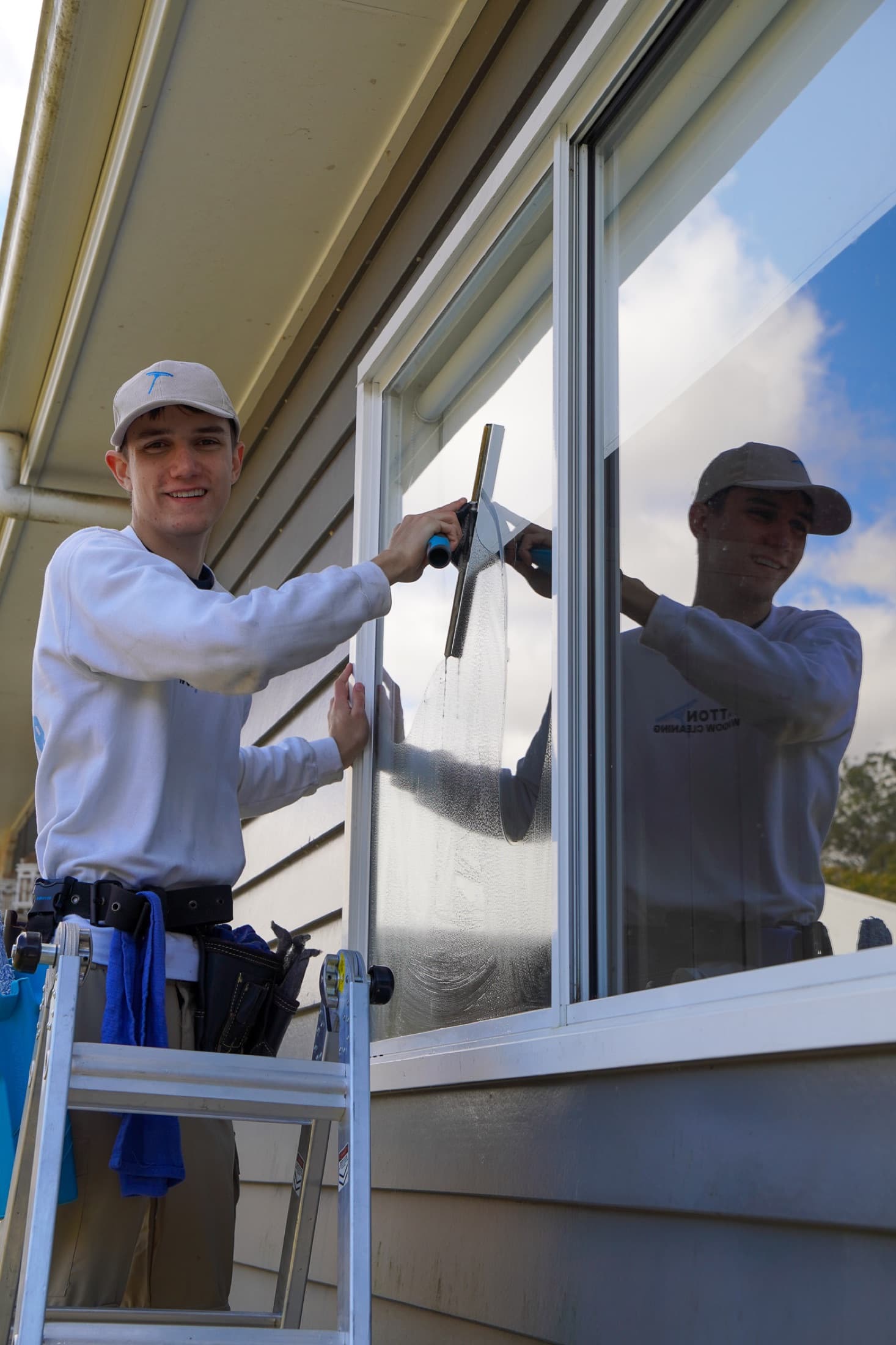 Xavier, owner of Gatton Window Cleaning, cleaning a window from the ladder